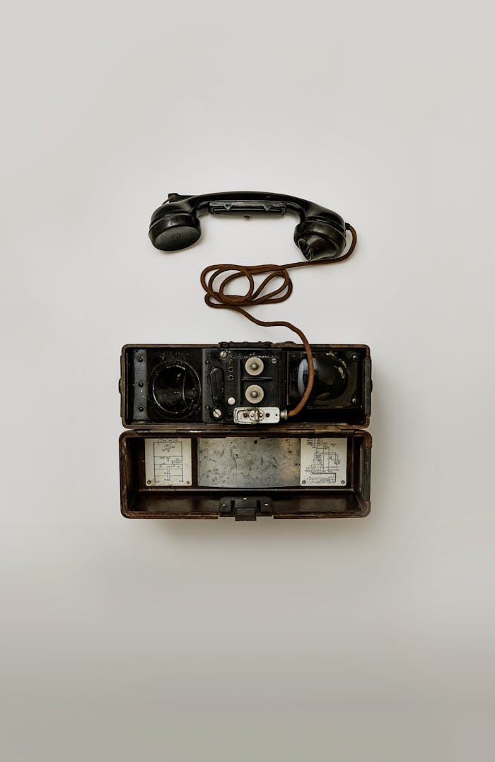 Close-up view of a vintage military field telephone with receiver and wires, showcasing antique technology.